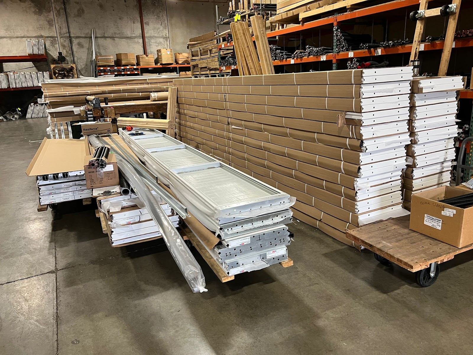Warehouse with stacked boxed garage door panels, tracks and parts on carts